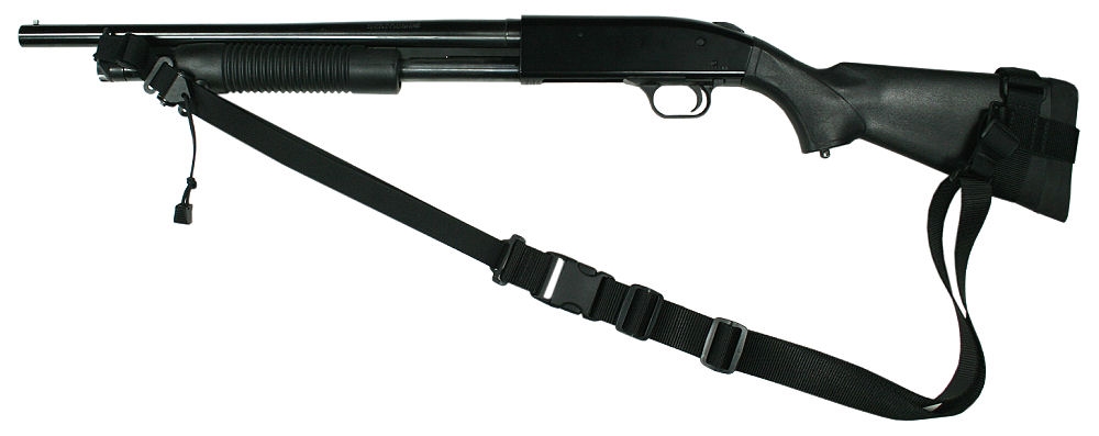 A black Mossberg 500/Maverick 88 pump‑action shotgun with a synthetic stock, tubular magazine, and attached sling, displayed horizontally on a flat surface.